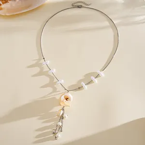 Nahaufnahme eines eleganten Muschelrosen-Anhängers und Perlen an einer Silberkette.