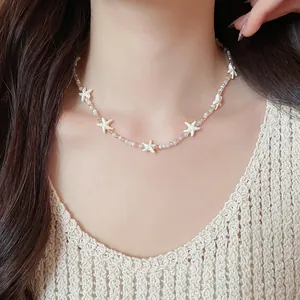 Close-up van een handgemaakte kralenketting met witte zeesterren en kristallen kralen