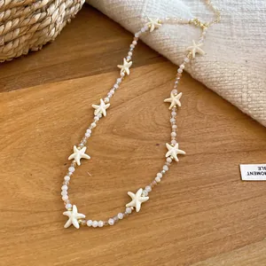 Detailweergave van een zomerse kralenketting met witte zeesterbedels en kristallen kralen