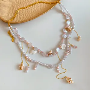 Dettaglio della catena da vita bohémien con perle e conchiglie e maglie dorate.