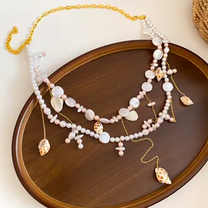 Dettaglio di una catena da vita boho con conchiglie naturali e perle per estate