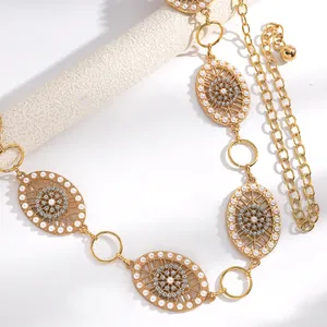 Détail d'une chaîne de taille dorée vintage en filigrane avec perles et strass scintillants