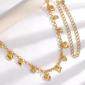 Détail macro d'une chaîne de taille dorée avec charms cœurs et gravures étoilées
