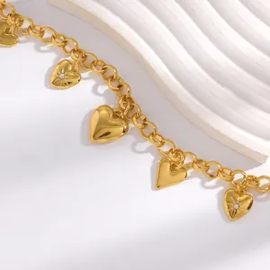 Détail macro d'une chaîne de taille dorée à breloques cœur bohème avec accents de strass.