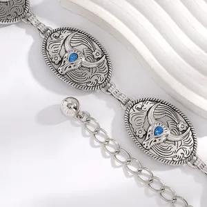 Gros plan de la chaîne de taille bohème en argent avec médaillons tête de taureau gemme bleue.