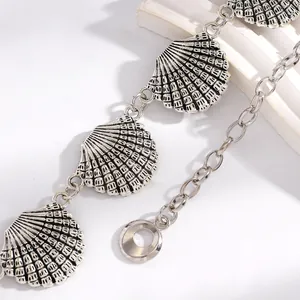 Gros plan détaillé d'une chaîne de taille avec pendentifs coquilles argentés style bohème
