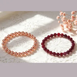 Detail shot of 6mm natural garnet and rose gold beaded bracelets on elegant white lace.