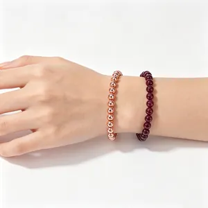 Close-up of 6mm natural garnet and rose gold copper bead bracelets on wrist
