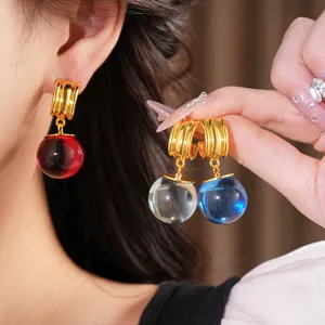 Gros plan de boucles d'oreilles boules en résine avec d'élégants clous plaqués or