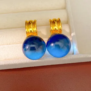 Gros plan de boucles d'oreilles rondes en résine bleue avec anneaux dorés.