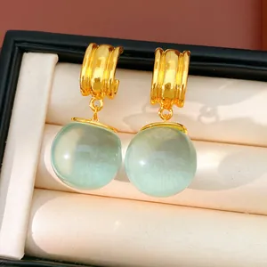 Vue détaillée de boucles d'oreilles dorées avec des perles en résine vert clair