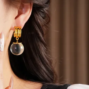 Vue détaillée de boucles d'oreilles créoles dorées avec perle en résine claire