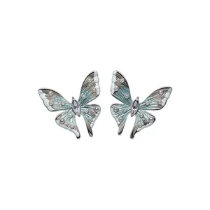 Elegante Schmetterlings-Ohrstecker mit blauem Emaille und lila Kristallen auf Silbernadeln.