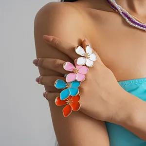 A detailed close-up shot of a vibrant multi-color enamel flower ring worn by a model.