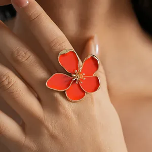 Detailed close-up view of a gold enamel orange flower ring worn on a finger for fashion