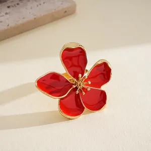 Detailed macro view of a red enamel flower ring with elegant gold metallic edges.