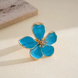 Detailed close-up view of a blue enamel flower ring with elegant golden metallic accents.