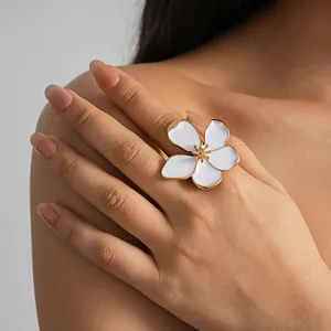 Macro view of an elegant large white enamel flower ring with gold trim on model