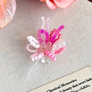 Dettaglio macro di un ciondolo a fiore in perline rosa e bianco fatto a mano per sabot