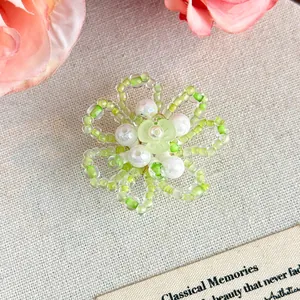 Dettaglio ravvicinato di un charm per scarpe a forma di fiore verde perlato e perle.