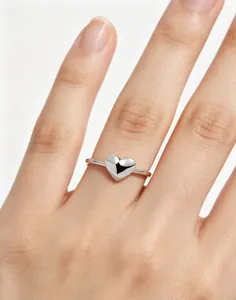 Close-up macro view of a polished S925 silver heart-shaped ring worn on a hand model