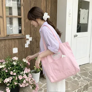 Détail du grand sac cabas en toile rose avec nœuds brodés et texte élégant