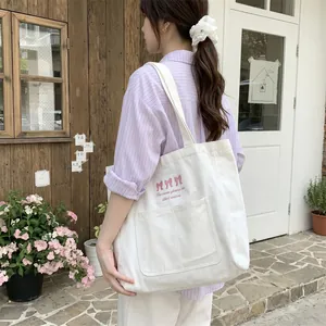 Détail du sac cabas en toile blanche avec nœuds roses brodés