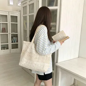 Detailed view of a large white lace canvas tote bag carried by a model in a library