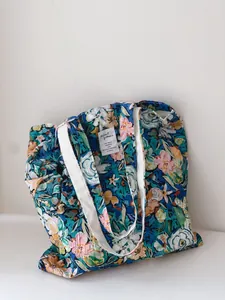 Detail of floral print cotton tote bag with natural wrinkled texture and white strap.