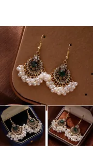 Close-up of Bohemian ethnic style earrings with green gemstones and pearl tassels.