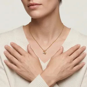 Close-up detail of a gold heart pendant necklace worn on a cream sweater