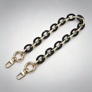 Detailed view of acrylic bag strap with alternating black resin and gold metal links.