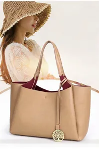 Vue détaillée d'un grand sac cabas en cuir grainé kaki avec un pendentif arbre doré.