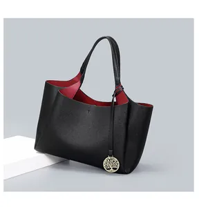 Vue détaillée d'un cabas en cuir grainé noir avec intérieur rouge et breloque or