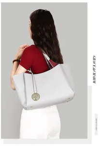 Vue latérale d'un grand sac cabas en cuir grainé gris avec un pendentif arbre doré.
