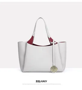 Sac cabas élégant en cuir gris avec intérieur rouge et breloque arbre doré détail