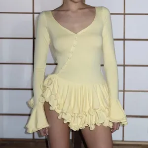Détail d'une robe jaune pâle à manches longues avec manches évasées et ourlet à volants