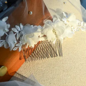 Close-up of bridal hair comb with elegant white flowers and pearls detail
