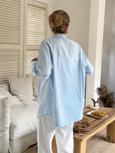 Back view of a light blue oversized cotton linen shirt styled in a cozy home setting