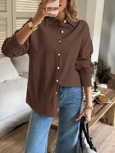 Mirror selfie view of a woman wearing a casual solid brown long-sleeved button-up shirt