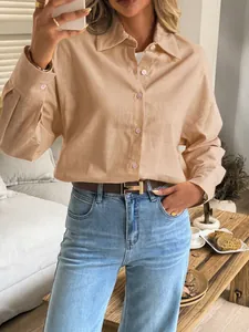Detail view of a woman wearing a chic beige long-sleeve shirt with casual denim jeans.