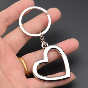 Creative silver metal hollow heart keychain charm for couples and gifts, handheld view