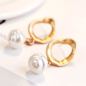 Close-up detail of golden irregular hoops with baroque pearl textures.