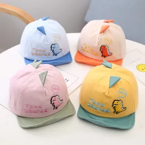 Detail view of four cute dinosaur baby baseball caps in different colors for toddlers