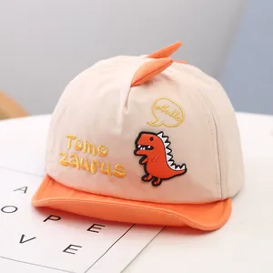 Close-up of a cute cartoon dinosaur patch on a stylish beige baby baseball cap