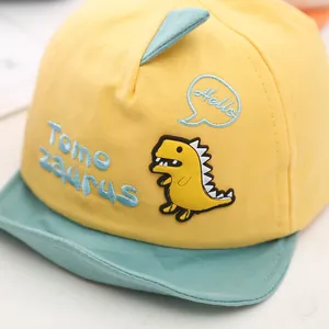 Close-up of yellow baby baseball cap with cute cartoon dinosaur patch and embroidery