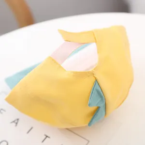 Detail of pink adjustable strap and dinosaur spikes on a yellow baby baseball cap