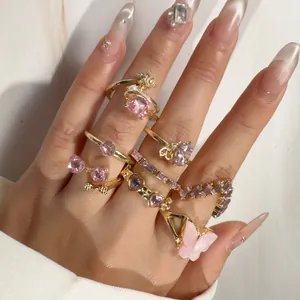 Exquisite close-up of sweet pink butterfly and heart crystal gold rings on hand