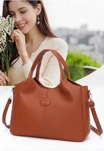 Close-up detail of large orange retro leather handbag featuring handles and shoulder strap