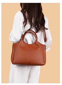 Detailed back view of a woman carrying a stylish large brown leather commuter handbag